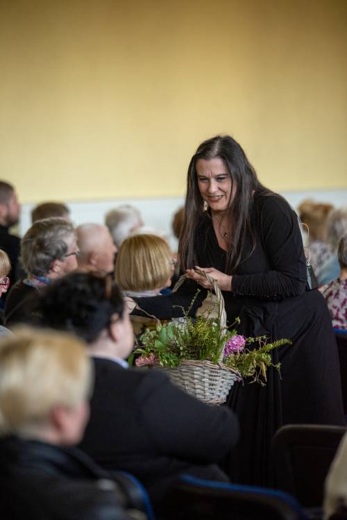 Zdjęcie przedstawia prowadzącą orkiestrę wręczającą kwiaty.